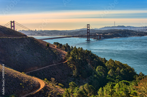 Panorama of the Golden Gate bridge at sunset with the Marin Headlands in the foreground, San Francisco skyline and colorful clouds in the background