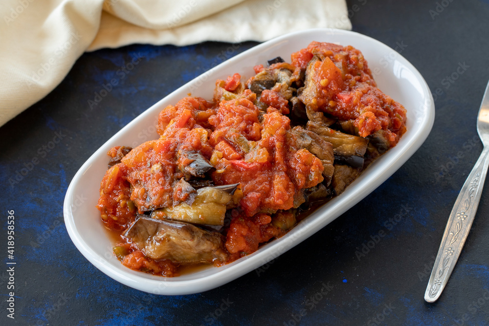 Grilled eggplant salad appetizer with tomato sauce (with eggplant sauce or saksuka). Traditional Middle Eastern meze beside the main course. Layout on dark wood Grilled eggplant salad appetizer with tomato sauce (with eggplant sauce or saksuka). Traditional Middle Eastern meze beside the main course. Layout on dark wood