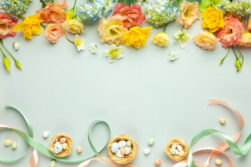 Happy Easter concept with easter eggs in nest and spring flowers. Easter background with copy space. Flat lay.