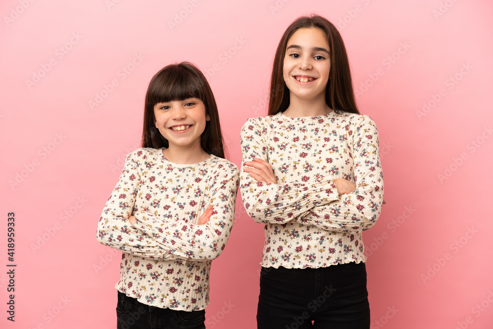 Little sisters girls isolated on pink background keeping the arms crossed in frontal position Little sisters girls isolated on pink background keeping the arms crossed in frontal position