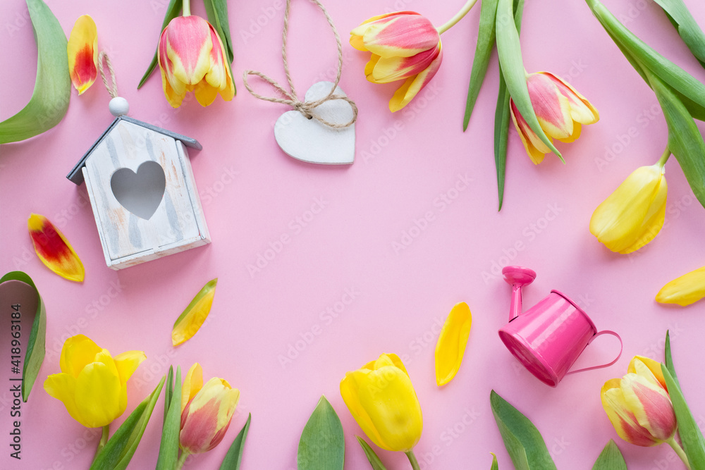 Fototapeta Colorful tulips, birdhouse, watering can wooden heard on pink background. Concept of Easter or spring time