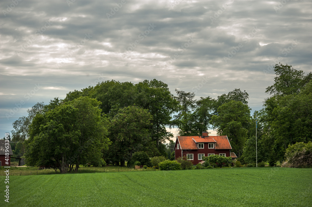 Old red house in Sweden landscape with a green field Old red house in Sweden landscape with a green field