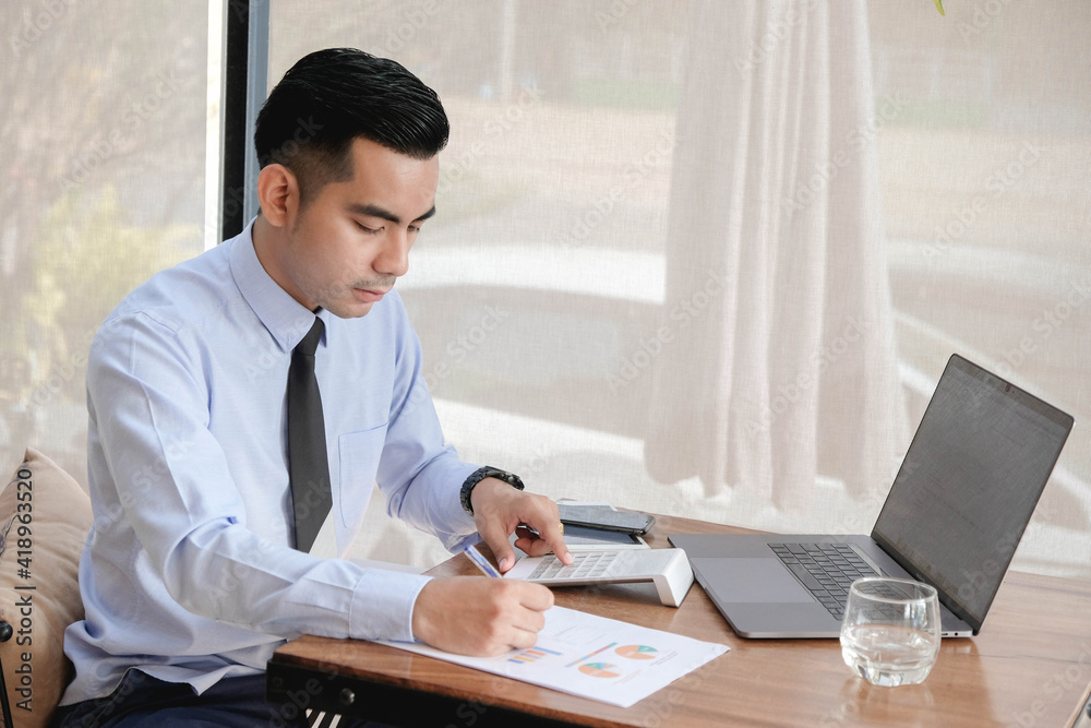 Fototapeta premium Young asian business man working with laptop, tablet and papers on desk at office.