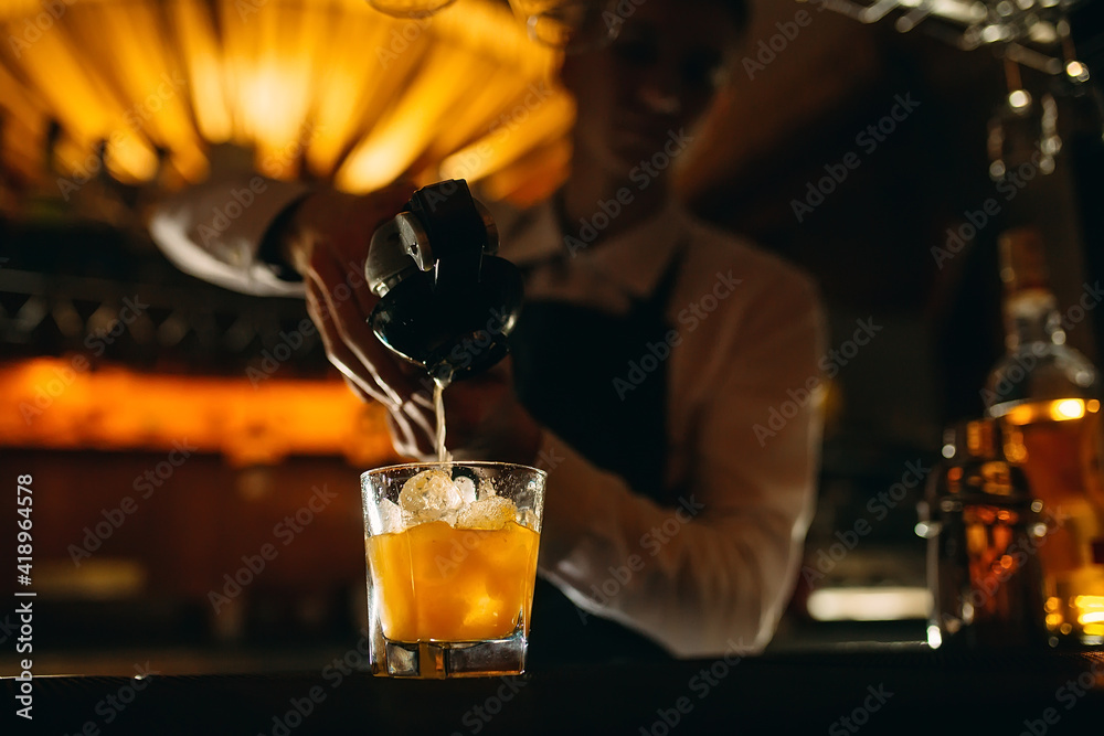 The bartender squeezes citrus juice into a cocktail.