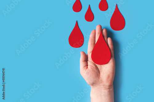 World hemophilia day concept with red blood drop simbol and hands on blue background photo