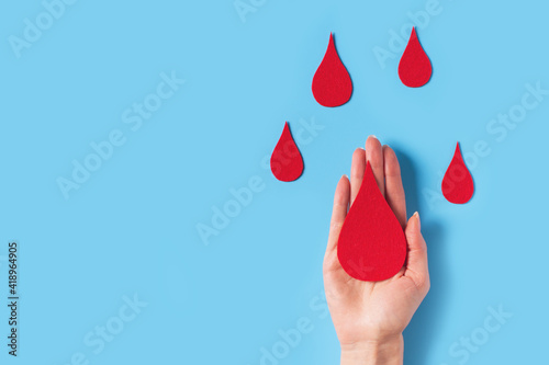 World hemophilia day concept with red blood drop simbol and hands on blue background photo