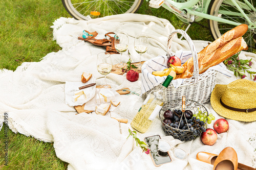 Summer - french style outdoor picnic in the garden. Wicker basket, food and wine.