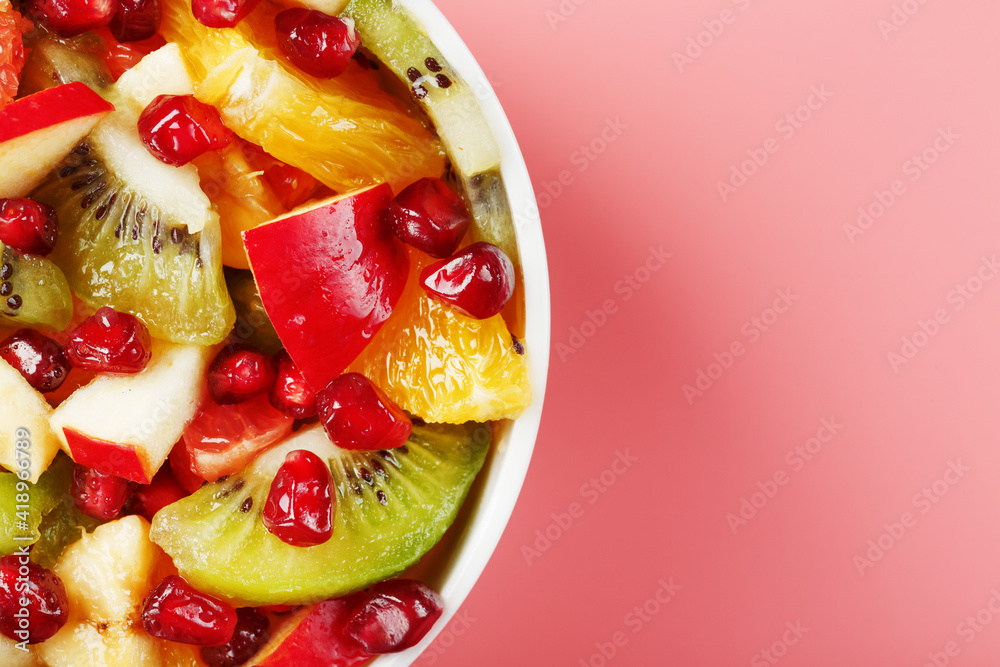 Fruit salad in a white cup on a pink background, free space for text. Fruit salad in a white cup on a pink background, free space for text.