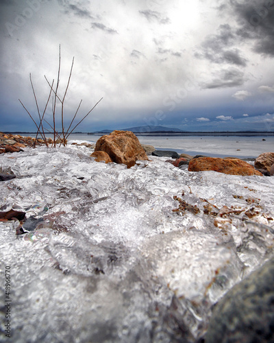 MIETKOW, POLAND - FEBRUARY 03, 2021: An ice-covered beach by the Mietkowski Lagoon, with the Sleza Mountain in the background. Mietkow near Wroclaw, Poland, Europe. photo