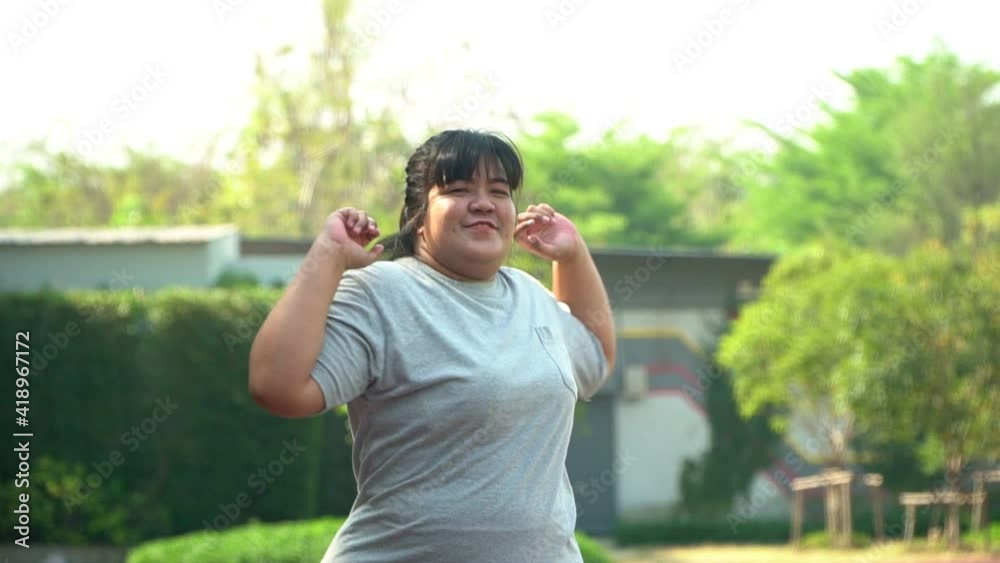 Happy overweight Asian women are warm-up before exercising in the park. Concept of Health care And weight loss through exercise - shot in slow motion. Happy overweight Asian women are warm-up before exercising in the park. Concept of Health care And weight loss through exercise - shot in slow motion.