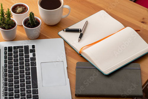 Wooden working desk with laptop computer, smartphone, office supplies and coffee