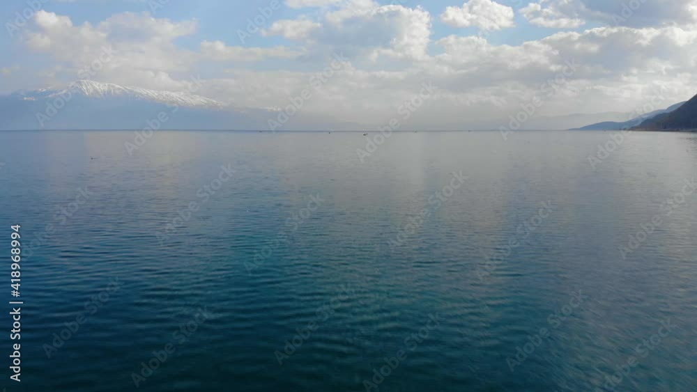 Turquoise water surface reflecting beautiful clouds on a spring day, fishing boats on lake Turquoise water surface reflecting beautiful clouds on a spring day, fishing boats on lake
