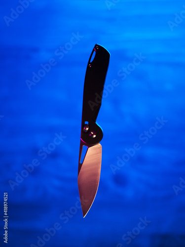 Levitating folding knife on neon trendy background photo