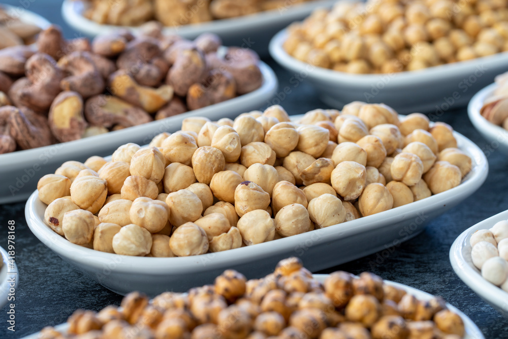 Hazelnuts in selective focus. Nuts on plate on a dark background. Walnut, Chickpeas, White Chickpeas, Dry mulberry, almond, cashew, pistachio. Types of nuts on the plate. Hazelnuts in selective focus. Nuts on plate on a dark background. Walnut, Chickpeas, White Chickpeas, Dry mulberry, almond, cashew, pistachio. Types of nuts on the plate.