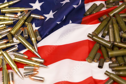 Many yellow 9mm and 5.56mm bullets and cartridges on United States flag. Concept of gun trafficking on USA territory or shooting range photo