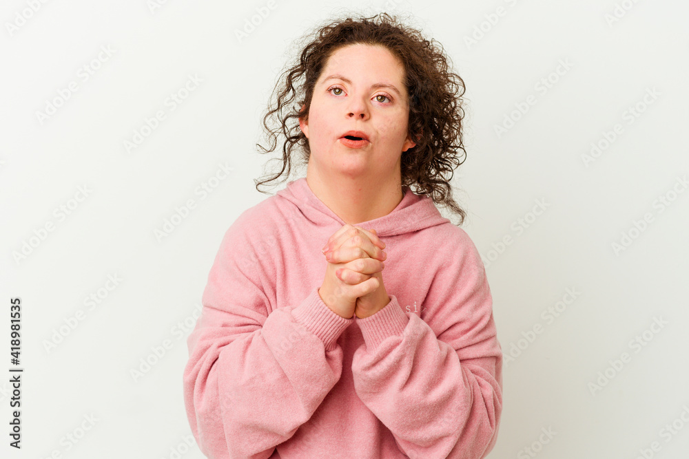 Woman with Down syndrome isolated praying for luck, amazed and opening mouth looking to front.