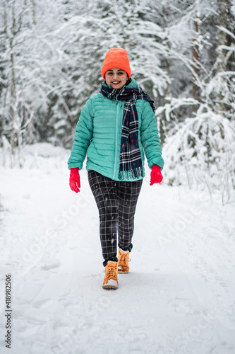 A woman wearing colourful cloth walking on the empty road with snow covered landscape