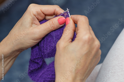  hands of woman knitting handmade clothes with spokes using  wool yarn. Concept of leisure activity.Knitting from yarn on  coarse spokes.