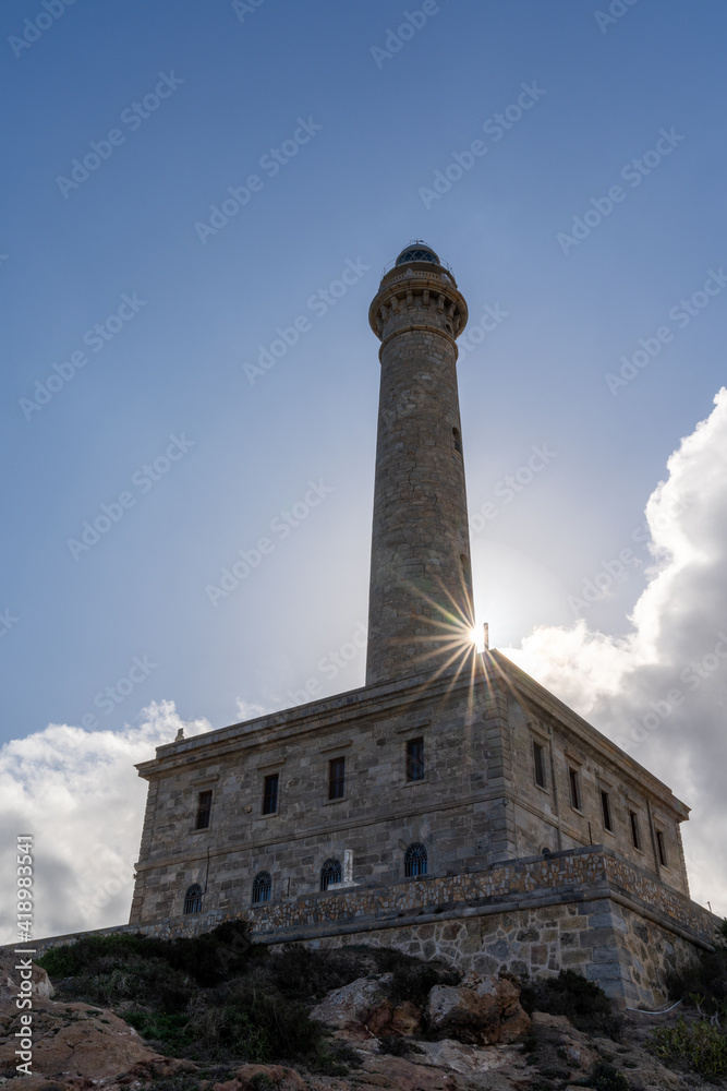 vertical close up view of the Cape Palos lighthouse in Spain with a sun star