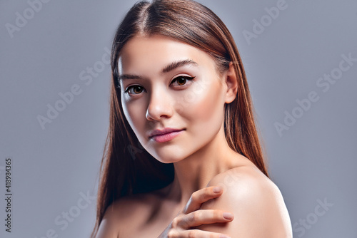 Beautiful young woman with clean perfect skin. Portrait of beauty model with natural nude makeup. Spa, skin care and wellness. Close up, gray background, copyspace.