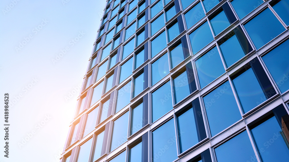Abstract closeup of the glass-clad facade of a modern building covered in reflective plate glass. Architecture abstract background. Glass wall and facade detail. Abstract closeup of the glass-clad facade of a modern building covered in reflective plate glass. Architecture abstract background. Glass wall and facade detail.