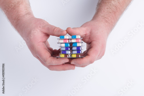 Close-up of hand holding medication blister packs of tablets and capsules against .Colorful pills and medicines in the hand.