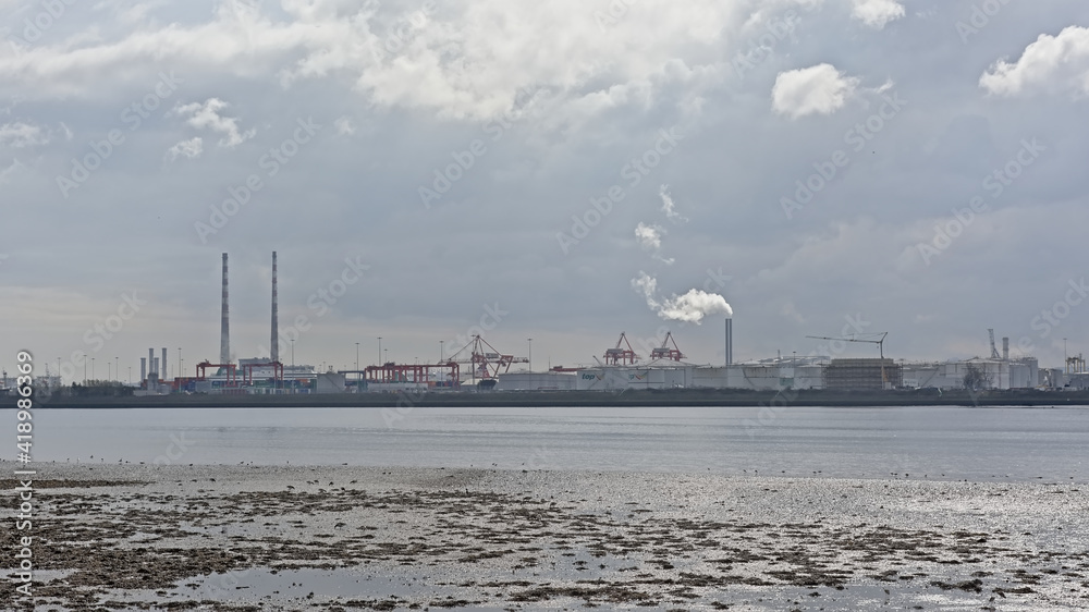Misty view from across the water on Poolberg peninsula, with the chimneys of the power generation station in Dublin, Ireland