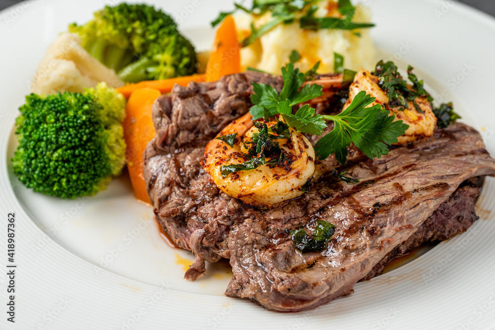 Delicious juicy grilled steak and shrimp with grilled broccoli and cauliflower. Surf and Turf style. Delicious juicy grilled steak and shrimp with grilled broccoli and cauliflower. Surf and Turf style.