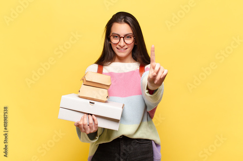 young pretty woman smiling and looking friendly, showing number one or first with hand forward, counting down. take aeay fast food concept photo