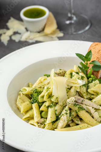 Penne pasta with pesto sauce, zucchini, green peas and basil.