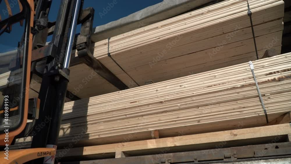 A forklift is loading wood planks into the truck. Transportation of ...