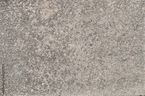 Textured rough surfaced concrete, for use as a background or texture overlay in photography and design projects. Grey with a hint of pink.
