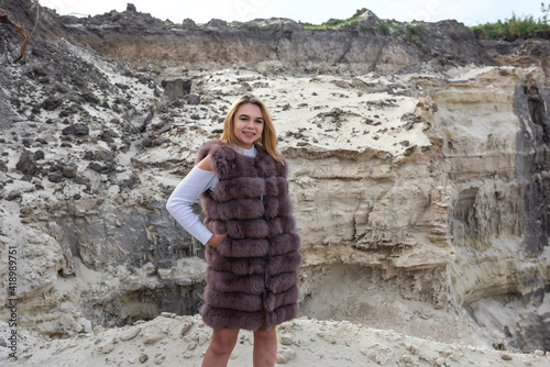 pretty girl in casual cloth and fur coat sand rocks