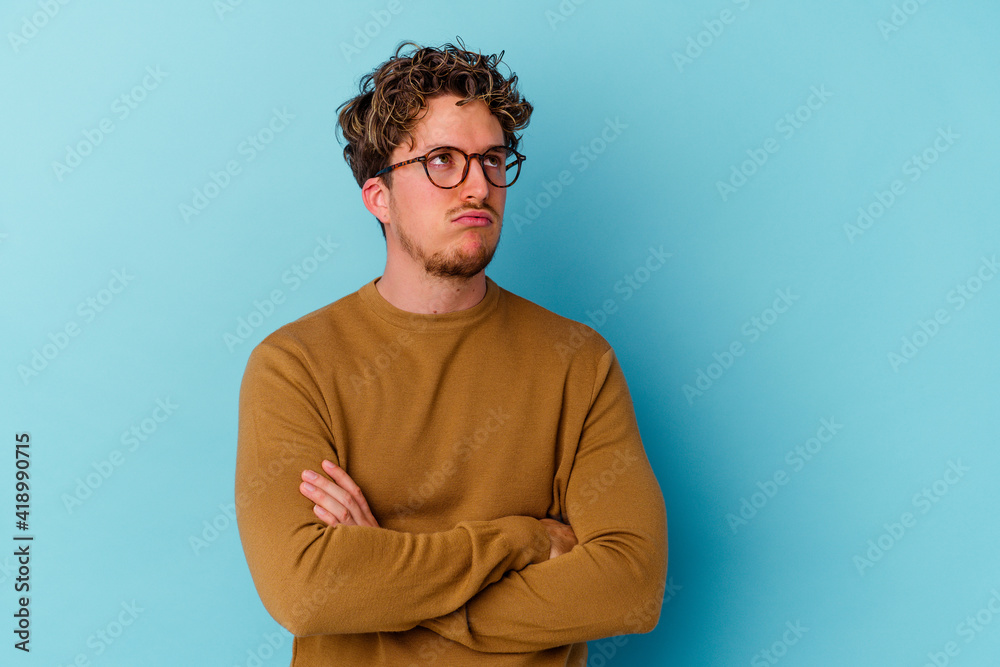 Fototapeta premium Young caucasian man wearing eyeglasses isolated on blue background tired of a repetitive task.
