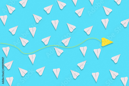 The concept of creativity and business. A yellow paper airplane flies among the white planes in search of a new solution. Blue background. Flat lay