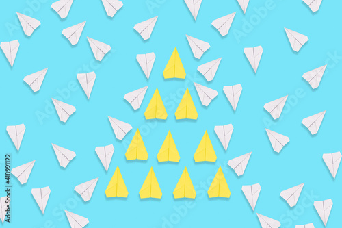 A group of yellow paper airplanes purposefully flies among the white planes. Blue background. Flat lay. The concept of leadership and teamwork Free Download A group of yellow paper airplanes purposefully flies among the white planes. Blue background. Flat lay. The concept of leadership and teamwork - GFXLoad