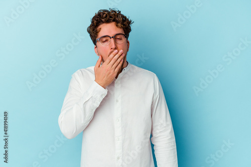 Young caucasian business man isolated on blue background yawning showing a tired gesture covering mouth with hand.