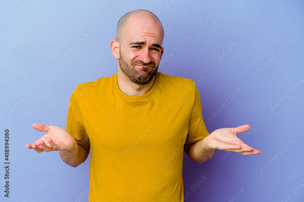 Young caucasian bald man isolated on purple background doubting and shrugging shoulders in questioning gesture. Young caucasian bald man isolated on purple background doubting and shrugging shoulders in questioning gesture.