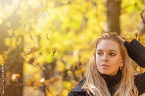 Portrait of attractive girl with hand in hair in autumn park. Horizontally. 