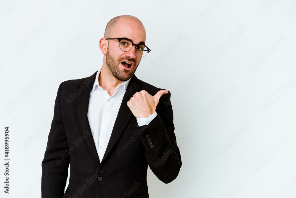 Young business caucasian bald man isolated on blue background points with thumb finger away, laughing and carefree. Young business caucasian bald man isolated on blue background points with thumb finger away, laughing and carefree.