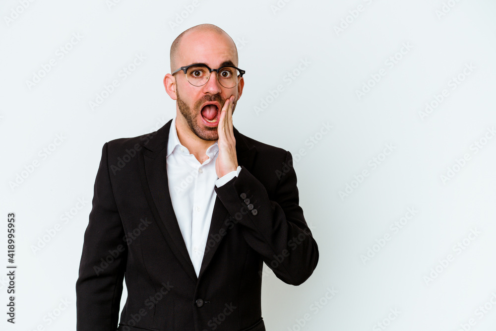 Young business caucasian bald man isolated on blue background shouts loud, keeps eyes opened and hands tense. Young business caucasian bald man isolated on blue background shouts loud, keeps eyes opened and hands tense.