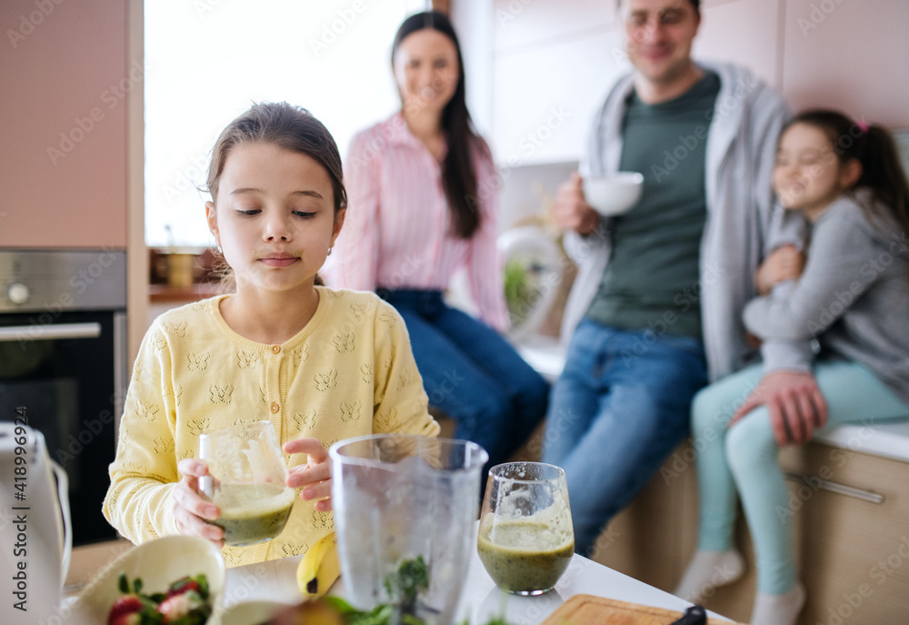 Small girls with parents indoors at home, preparing fruit smoothie drink. Small girls with parents indoors at home, preparing fruit smoothie drink.