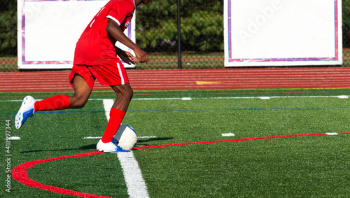 Soccer player in red uniform dribbling the ball downfield photo