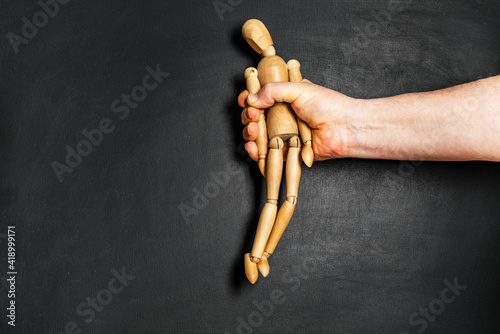 Obraz na płótnie wooden man is grabbed by a man hand. The concept of helplessness and submission w salonie