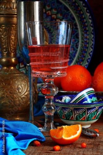 Oriental still life with red wine and oranges on wooden background
