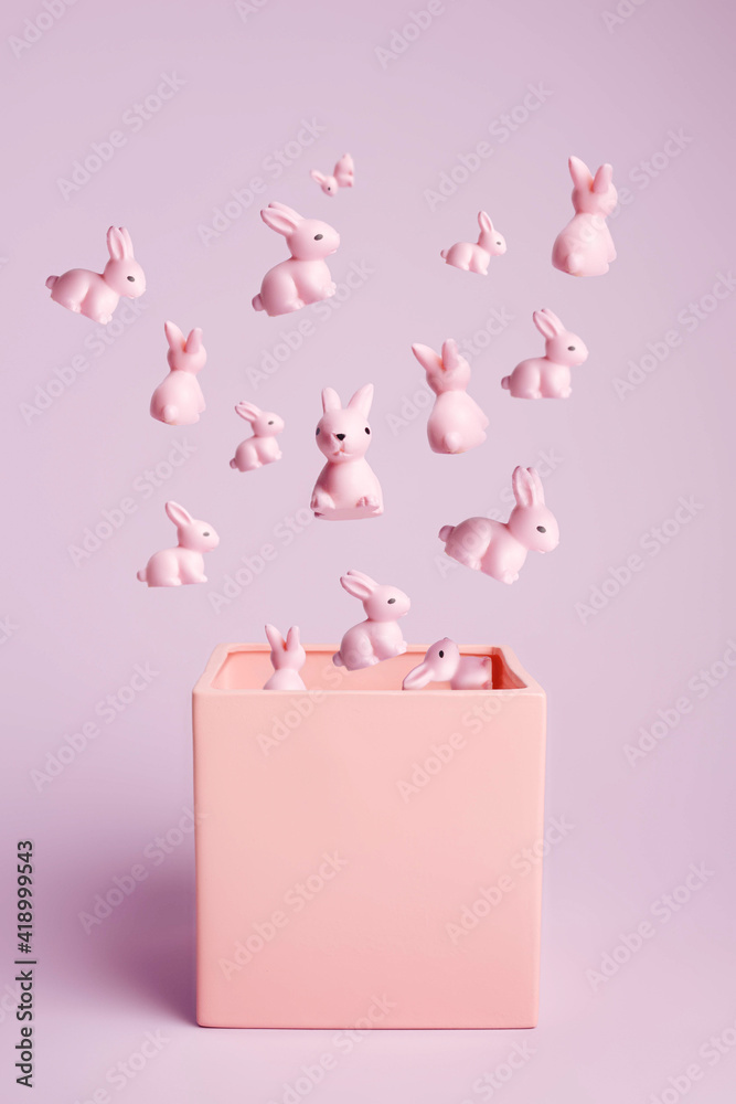 Creative layout with bunch of pink bunnies and rabbits flying out of box on pastel pink background. Minimal Easter holiday concept. Contemporary spring holiday animal layout. Creative layout with bunch of pink bunnies and rabbits flying out of box on pastel pink background. Minimal Easter holiday concept. Contemporary spring holiday animal layout.