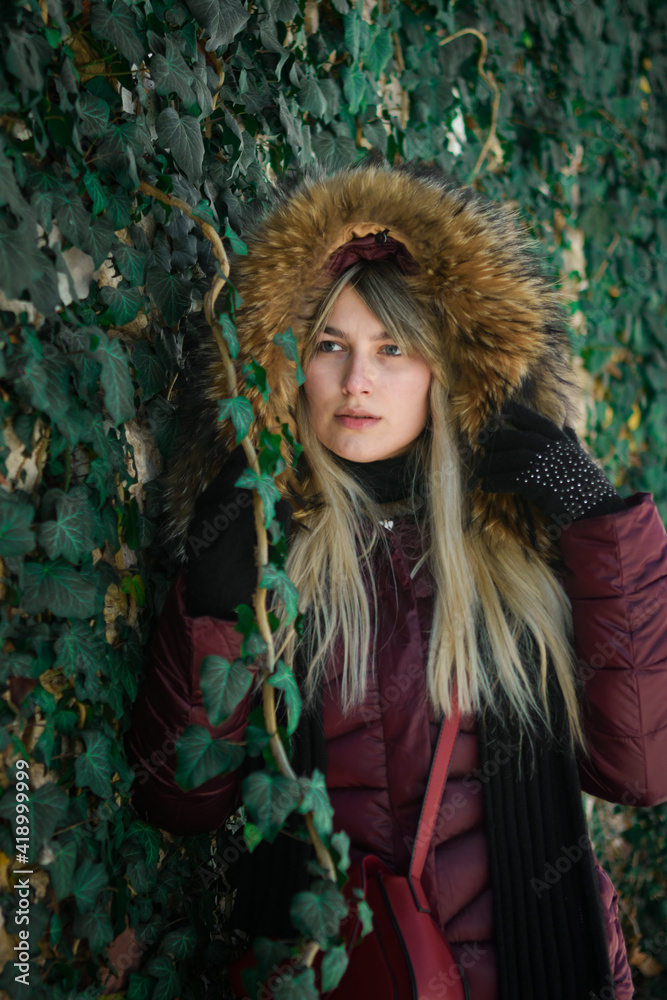 Fototapeta premium Portrait of a young girl from eastern Serbia. Posing by the wall covered with green leaves.