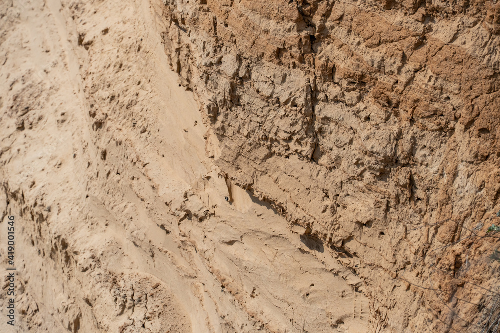 The steep slope of a sand mining quarry. Background and texture of sand. soil layers on a plot of the cut of the soil during a geological survey.