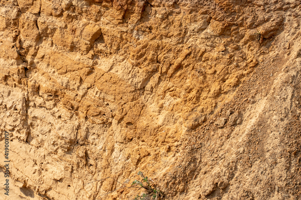 The steep slope of a sand mining quarry. Background and texture of sand. soil layers on a plot of the cut of the soil during a geological survey. The steep slope of a sand mining quarry. Background and texture of sand. soil layers on a plot of the cut of the soil during a geological survey.
