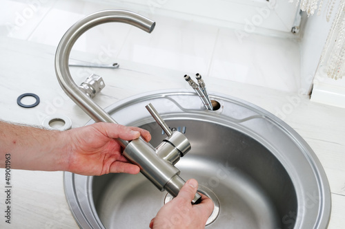 Close-up plumber hands holds a new faucet for installing into the kitchen sink, plumbing work or renovation